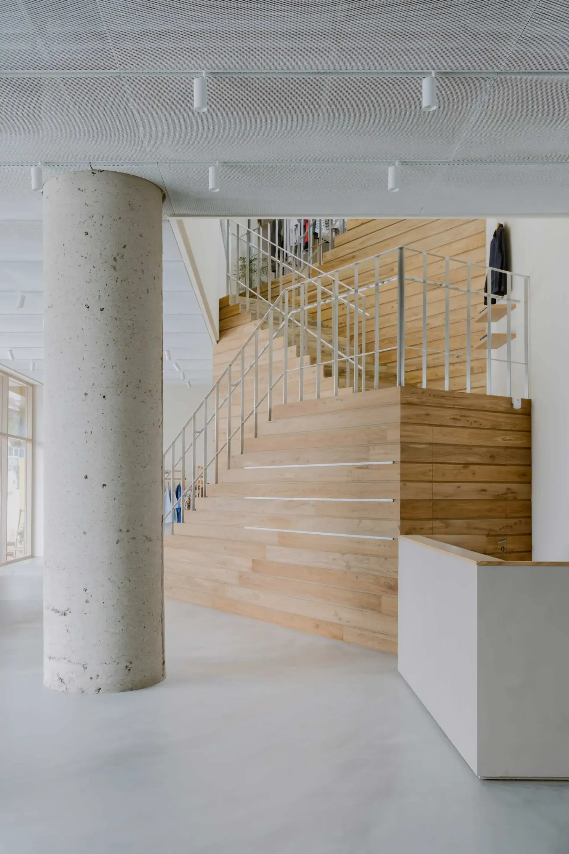 Modern office space featuring wooden stairs and a concrete pillar