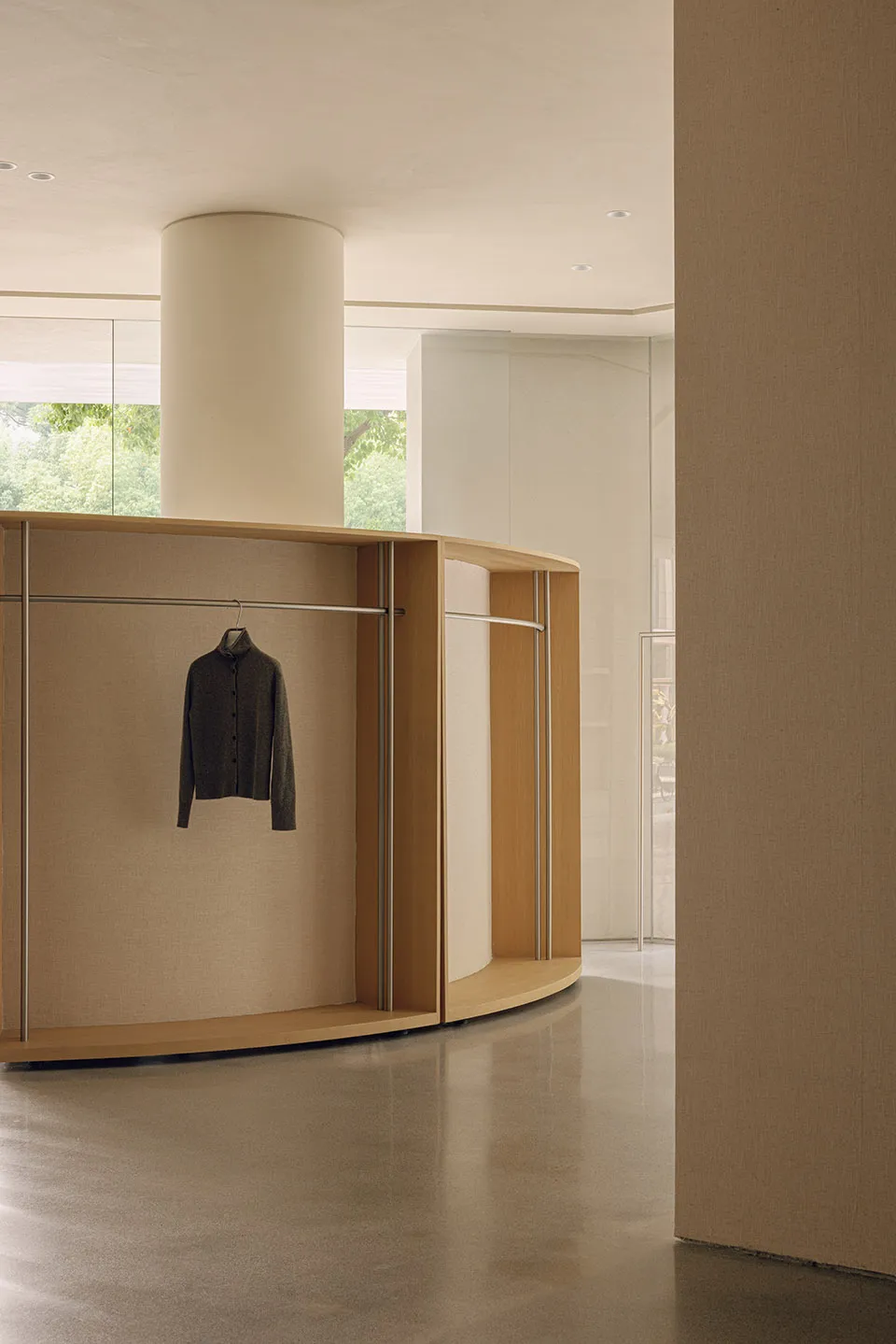 A modern, minimalist wardrobe with curved walls and a single shirt hanging on it.