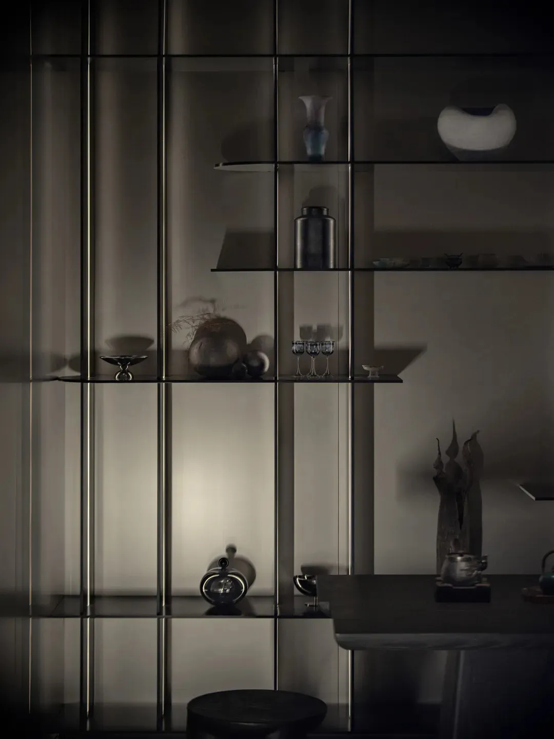 A modern, minimalist indoor display featuring glass shelves with various decorative items.