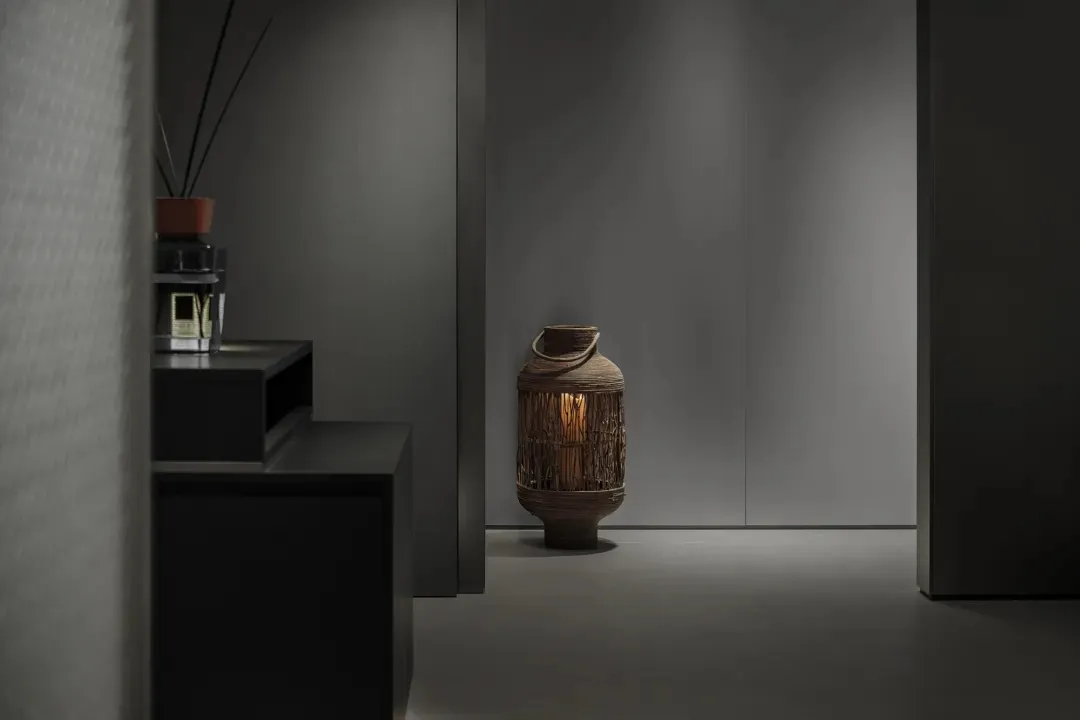 A minimalist lobby with metal furniture and a small lantern on the floor.