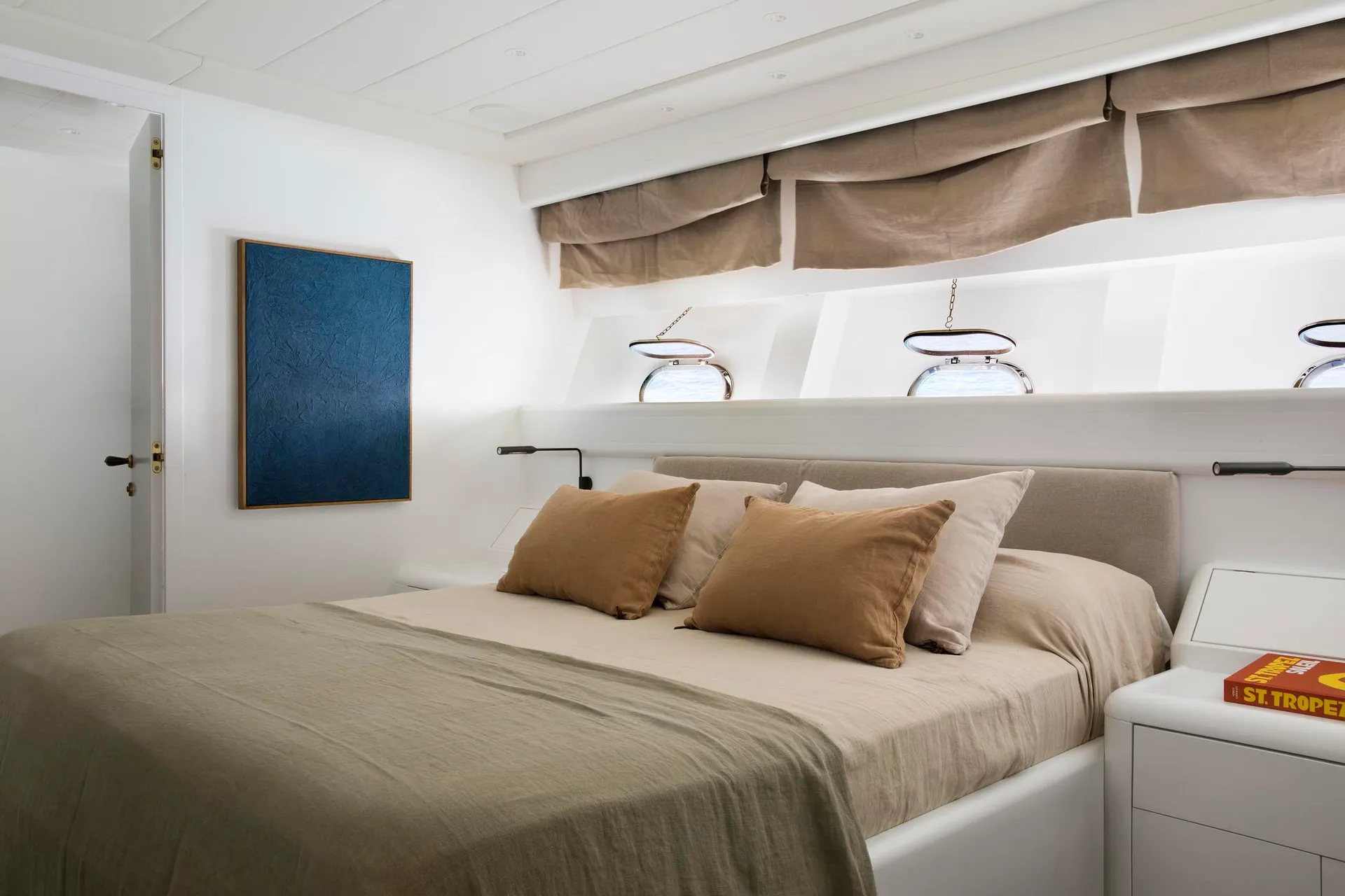 A minimalist bedroom featuring a bed adorned with brown and beige linen pillows and a matching comforter, set against a white
