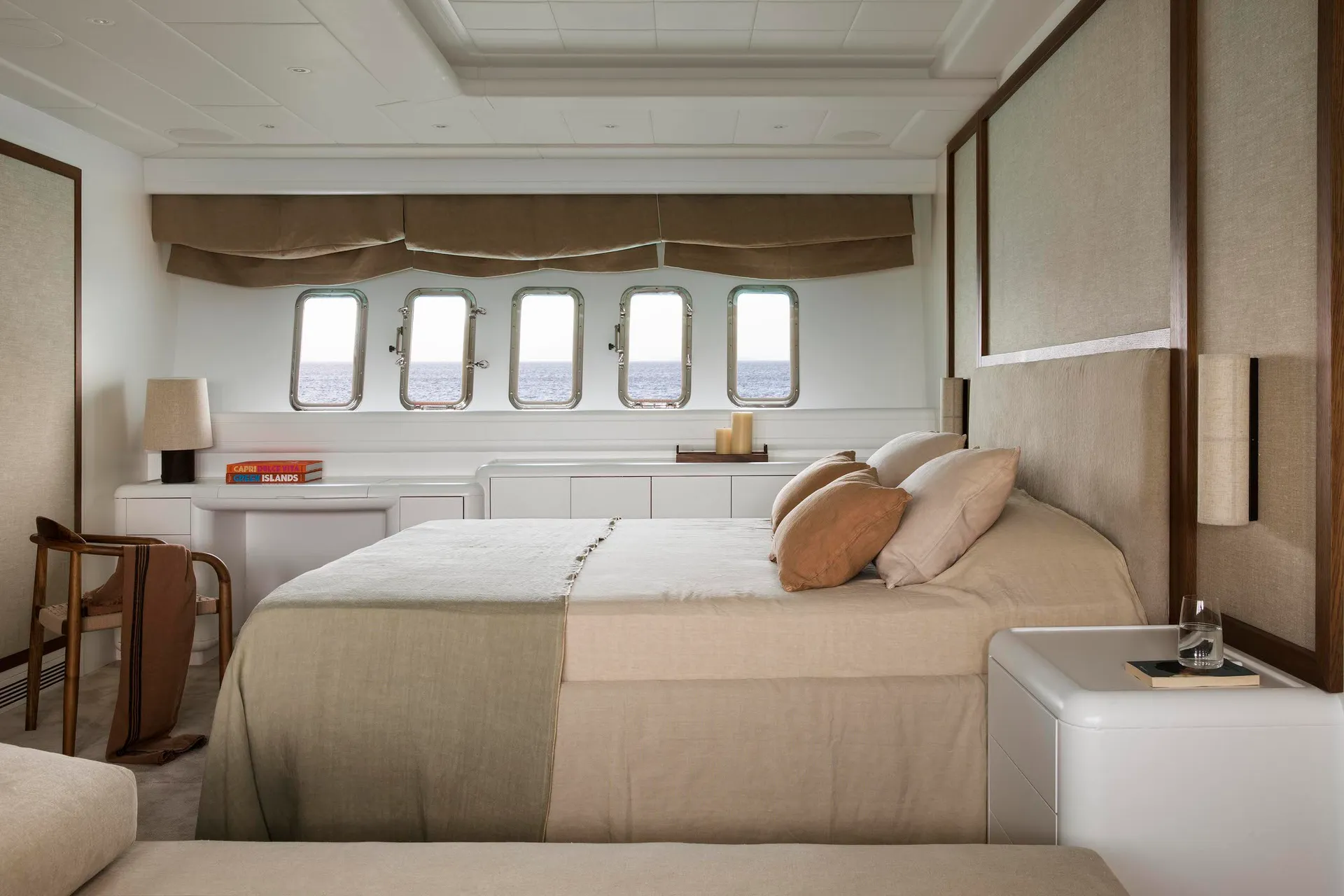 A modern, minimalist bedroom featuring a comfortable bed with light-colored fabric bedding, a grey upholstered headboard, and