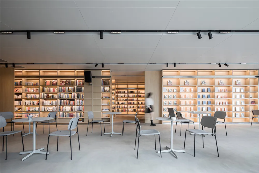 A minimalist library interior featuring neutro-wood materials and an organized shelving system.