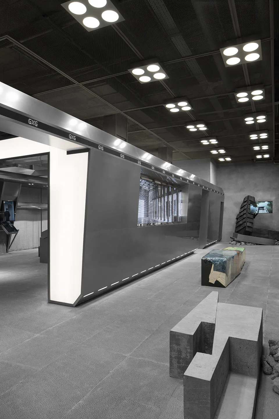 A minimalist atrium with industrial concrete walls and illuminated panels.
