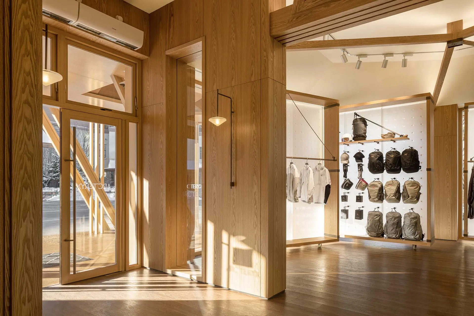 A retail interior with wooden panels and clothing racks displaying apparel.