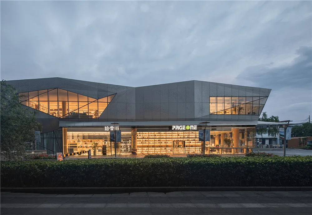 Modern retail storefront with a glass facade, illuminated interior, and exterior space.