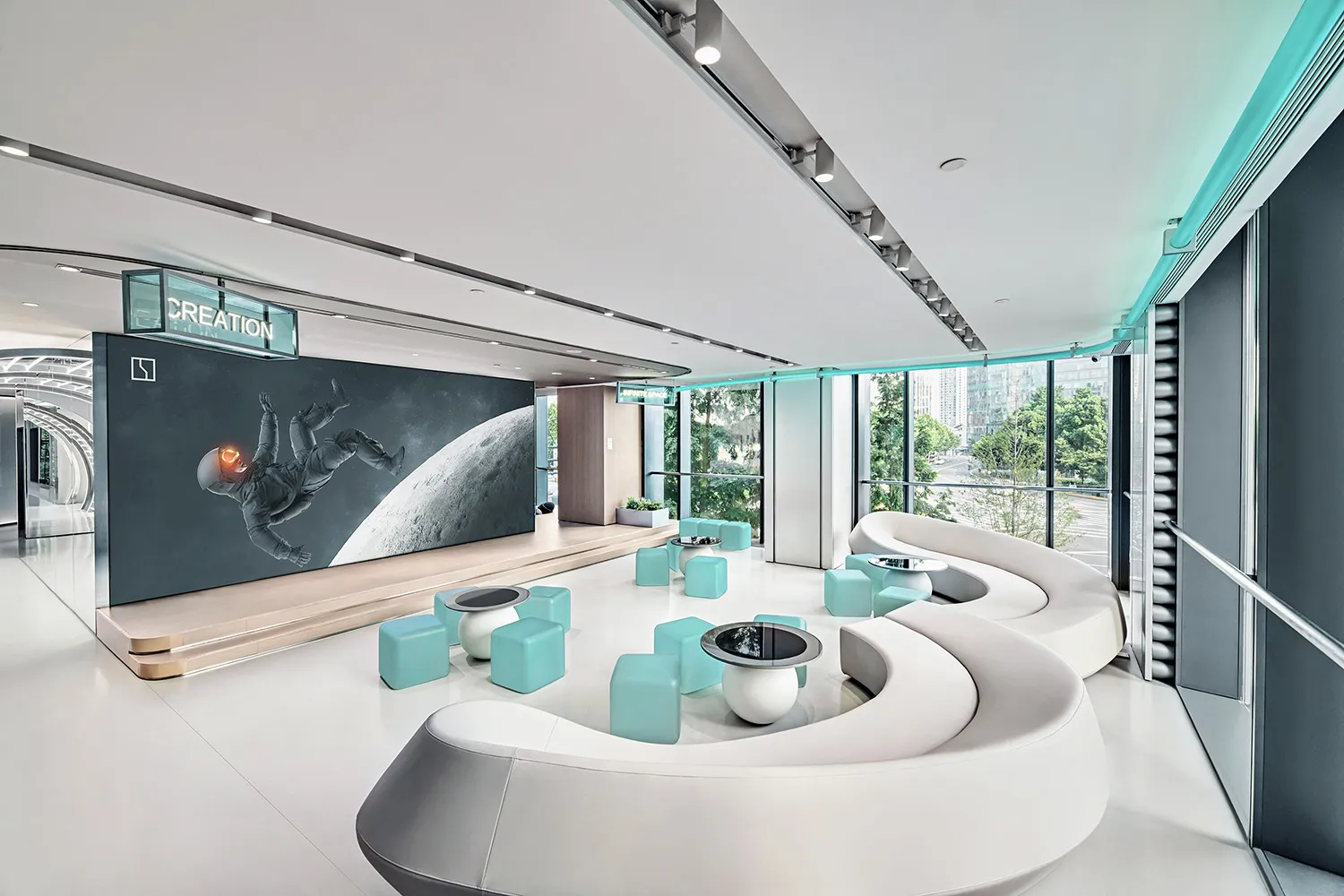 A modern office lounge featuring white and turquoise seating with concrete flooring and concrete seating areas, illuminated b