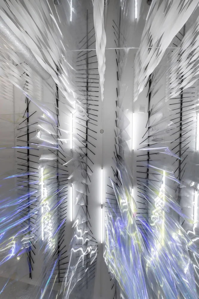An abstract art installation featuring translucent, iridescent fabric panels suspended from the ceiling.