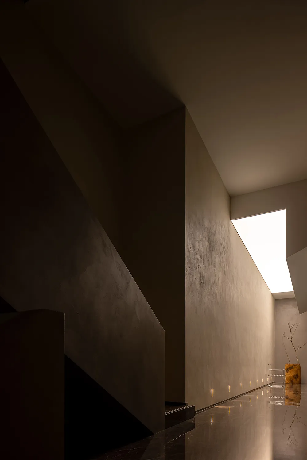 A minimalist interior featuring a concrete courtyard with natural light filtering through a skylight.