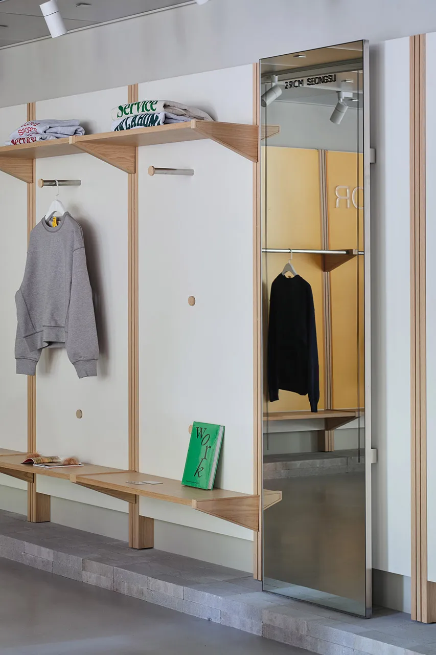 A modern clothing store interior with wooden shelving and a glass wall