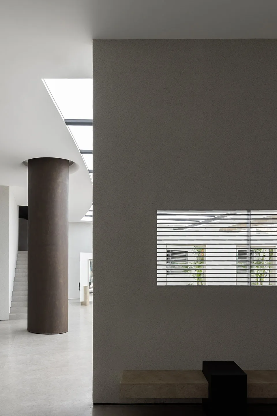 A modern interior design featuring concrete walls and a large skylight.