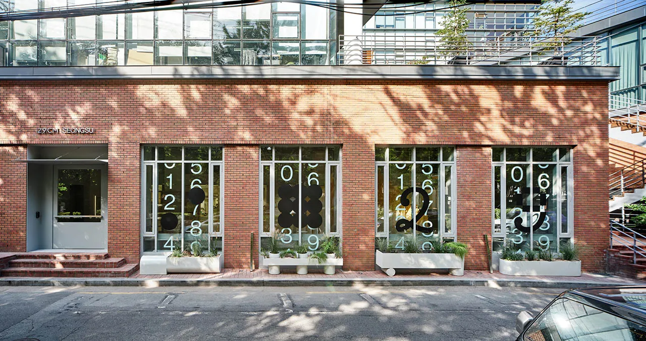 Modern architectural exterior featuring planters with various numbers on a brick facade.