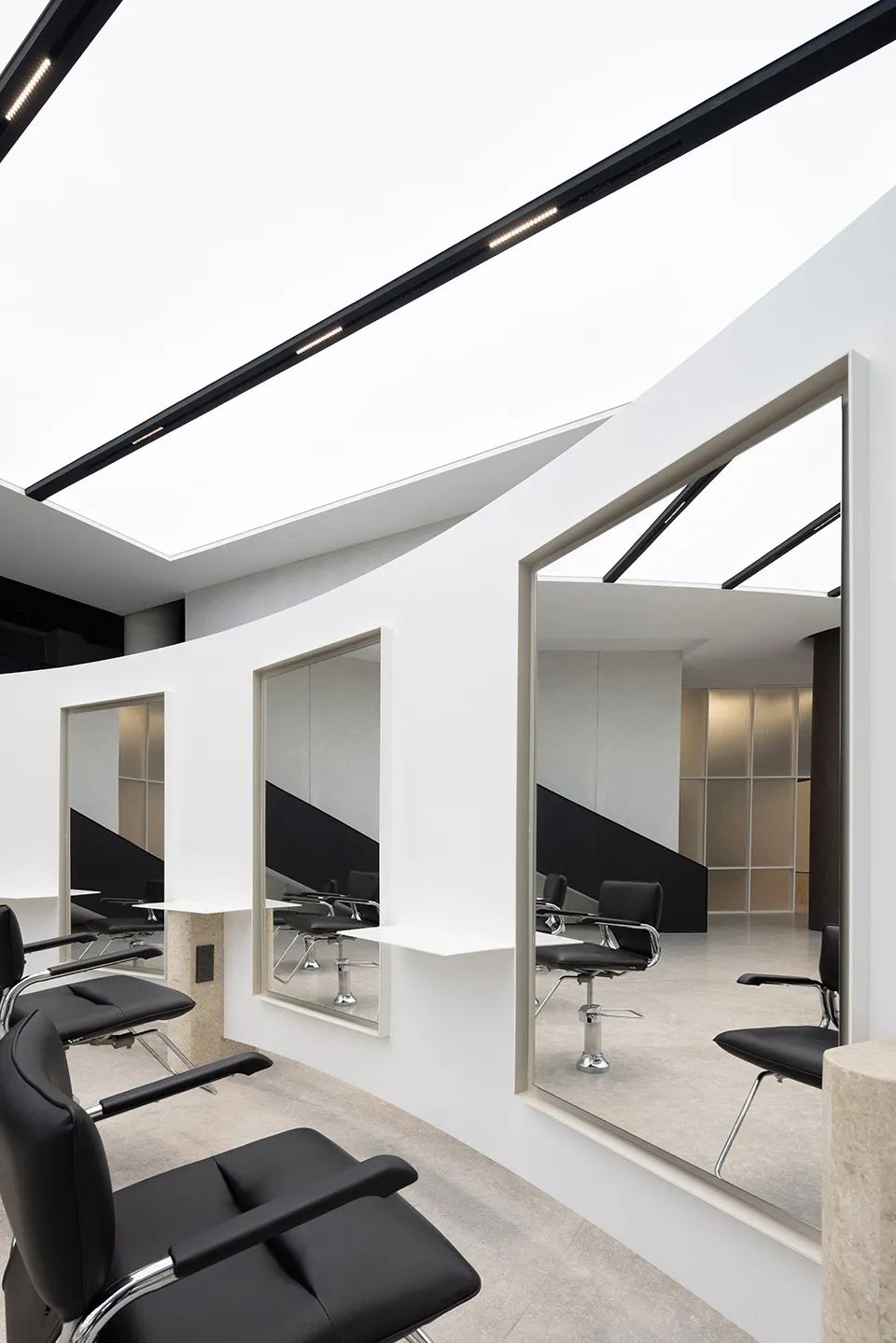 A modern minimalist hair salon with black and white color scheme and metallic black furniture.