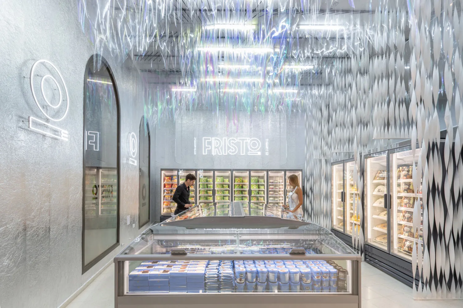 A modernista retail space with a glass ceiling and an array of products displayed in refrigerators and freezers.