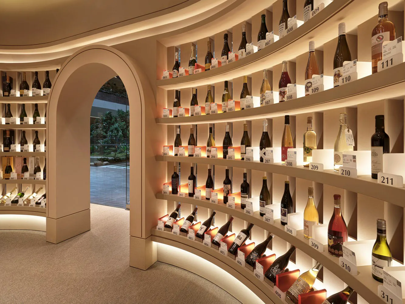 A well-lit interior space featuring a curved wall dedicated to displaying bottles of wine.
