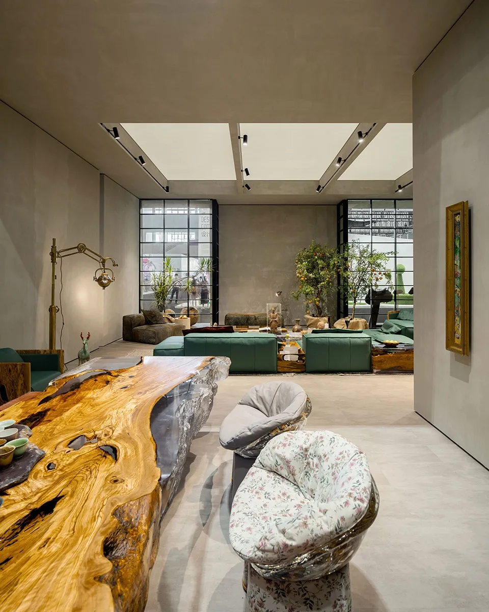 A modern industrial living room featuring a metal structure, green sofas, and a wooden coffee table.