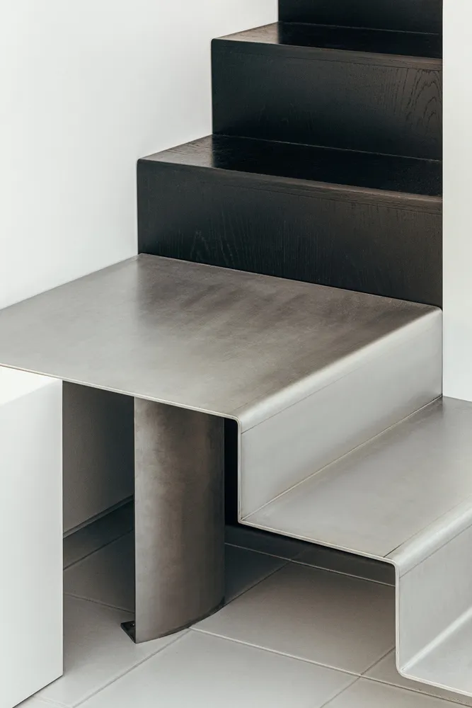 Modern, minimalist interior design featuring a sleek, metallic staircase with wooden steps.