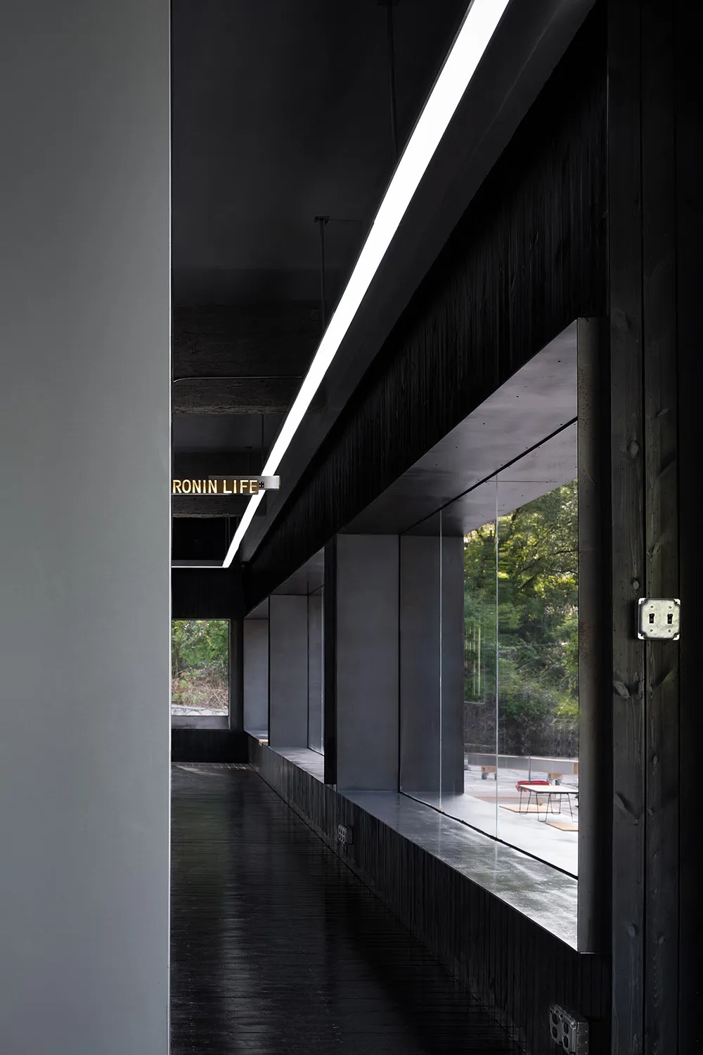 A modern office space featuring black wood elements, with natural light streaming through expansive windows.