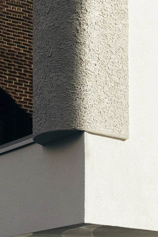 White concrete exterior wall with textured finish and shadow details.