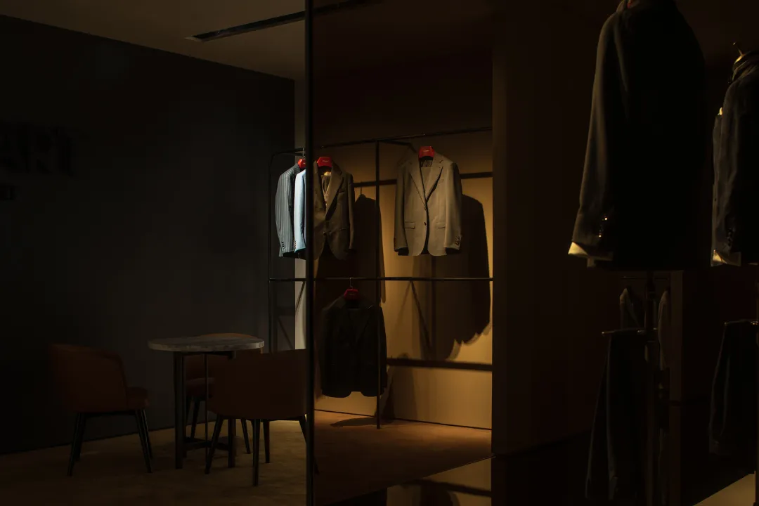 A clothing store display featuring suits hanging on racks with minimalist design elements.