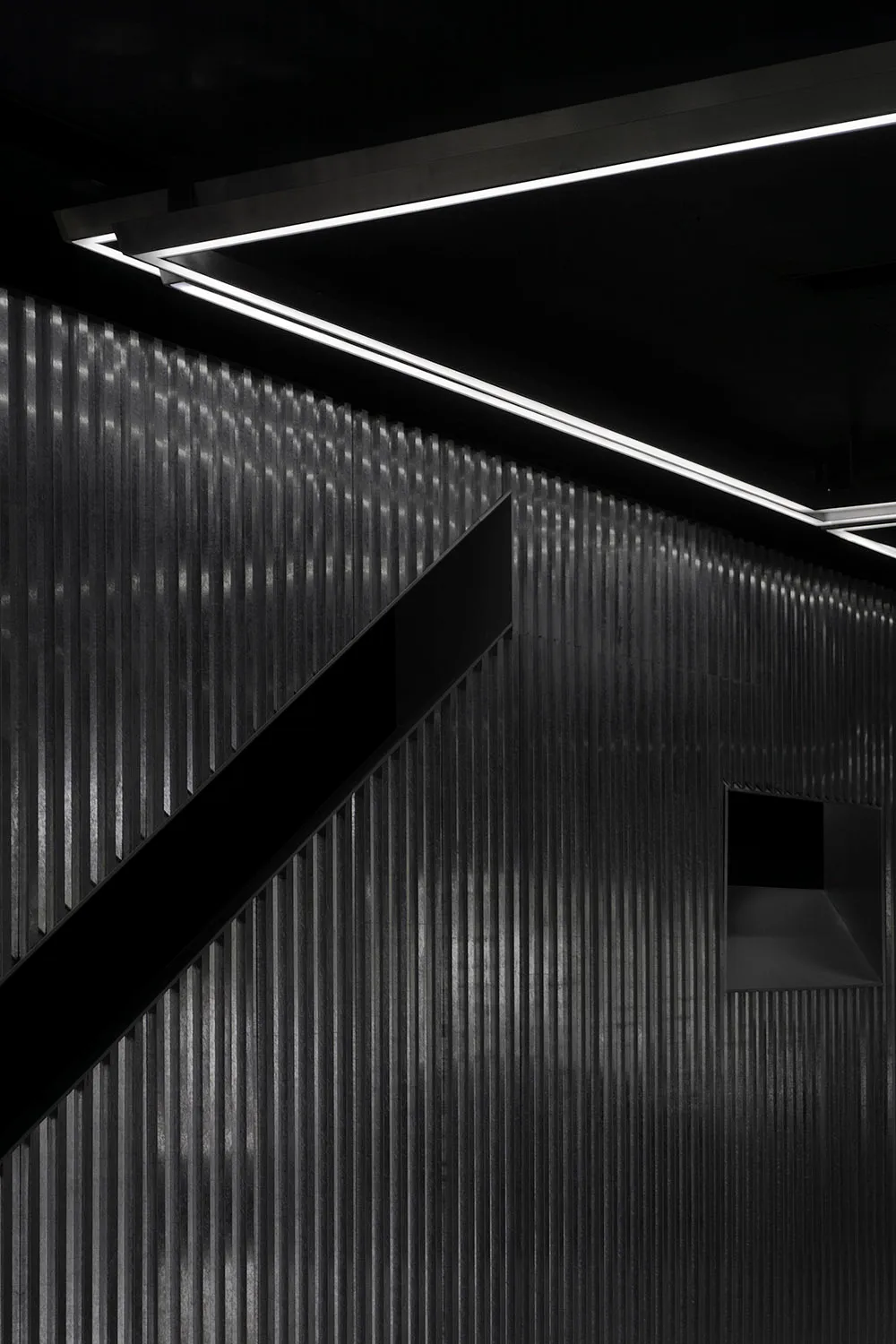 Modern industrial interior with corrugated metal walls and minimalist lighting.
