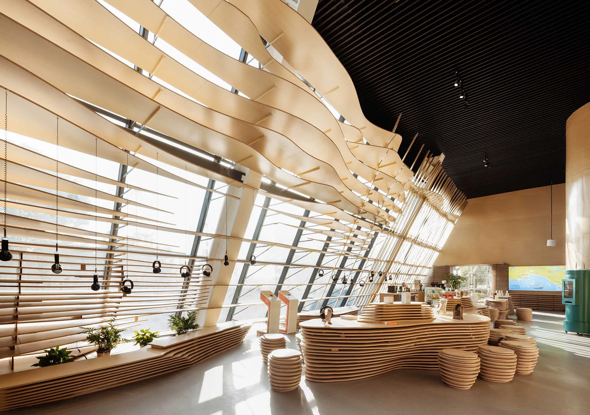 Lobby area of a modern coffee shop with wooden elements and headsets hanging on the ceiling.