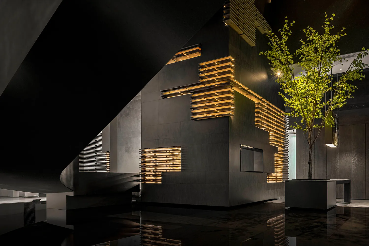 A modern hotel lobby featuring dark metallic cladding and illuminated wood slats.