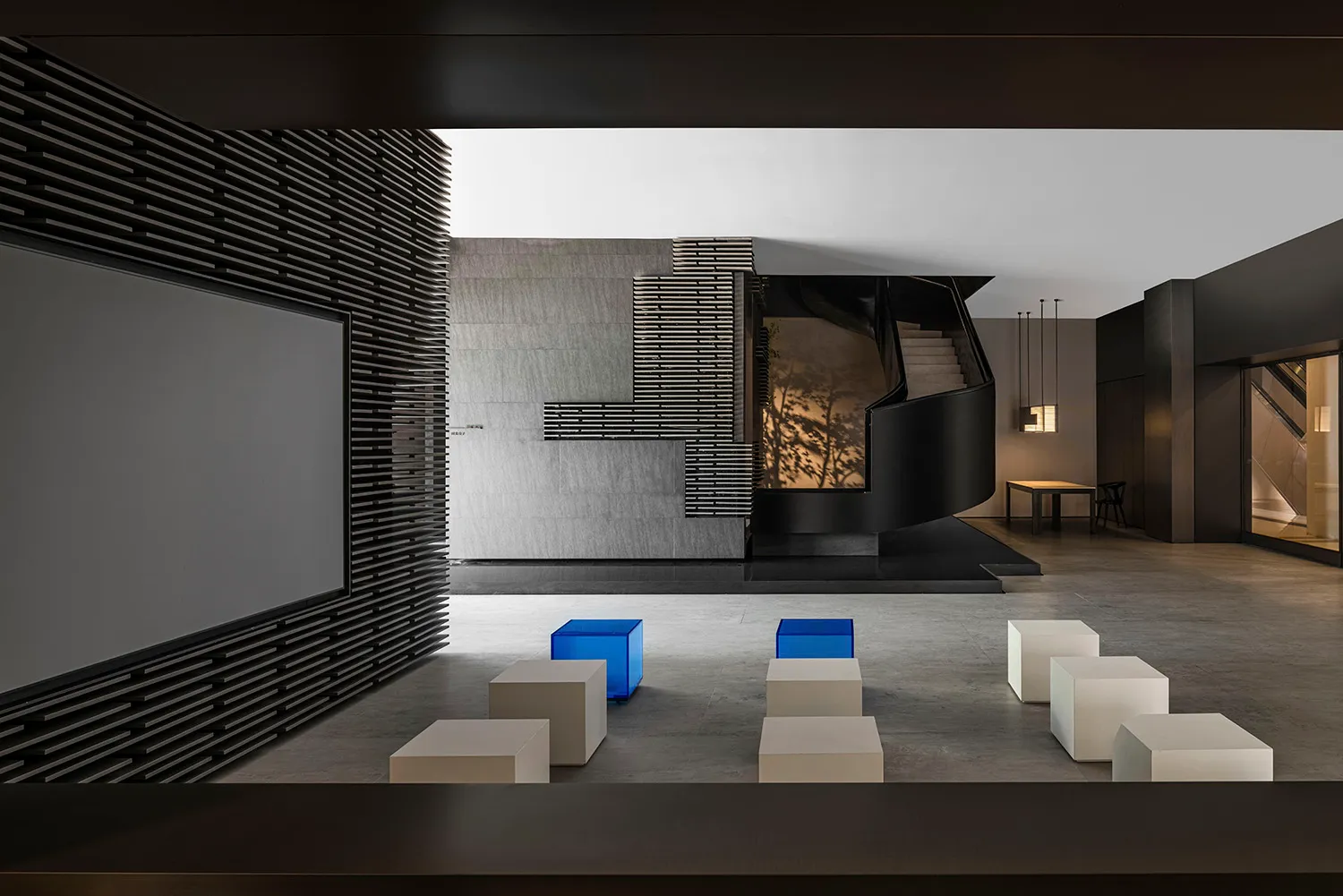 Modern lobby with concrete walls, metal staircase, and concrete floor.