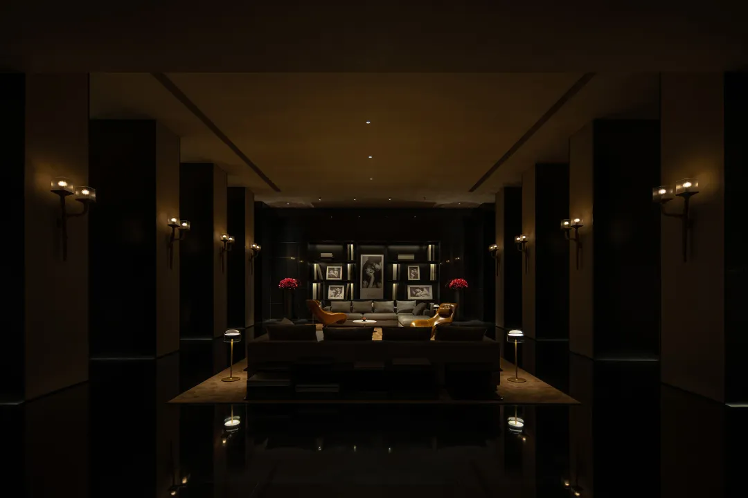 A minimalist modern lobby features a sleek and contemporary design with dark walls and floors, mixed materials, and illuminat