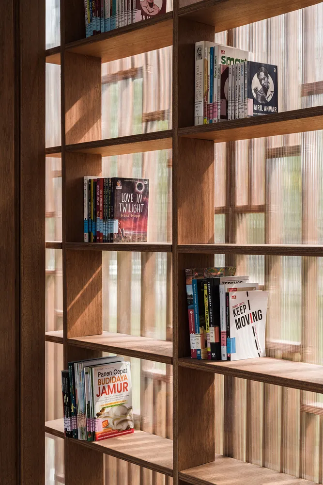 Books neatly arranged on a wooden bookshelf inside a window.