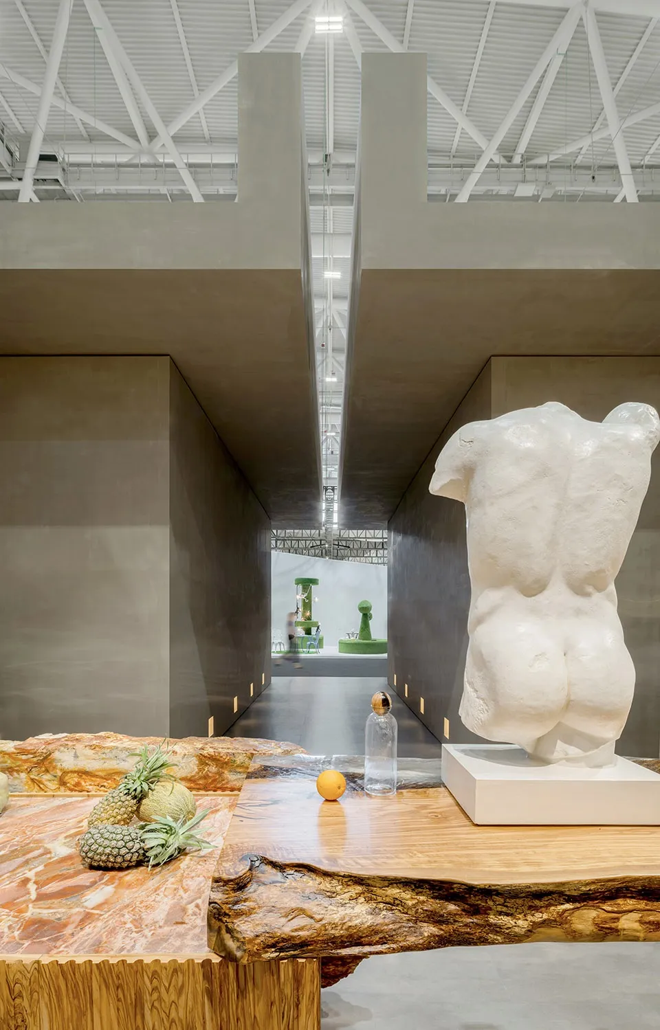 A modern exhibit hall featuring marble sculptures and tables.