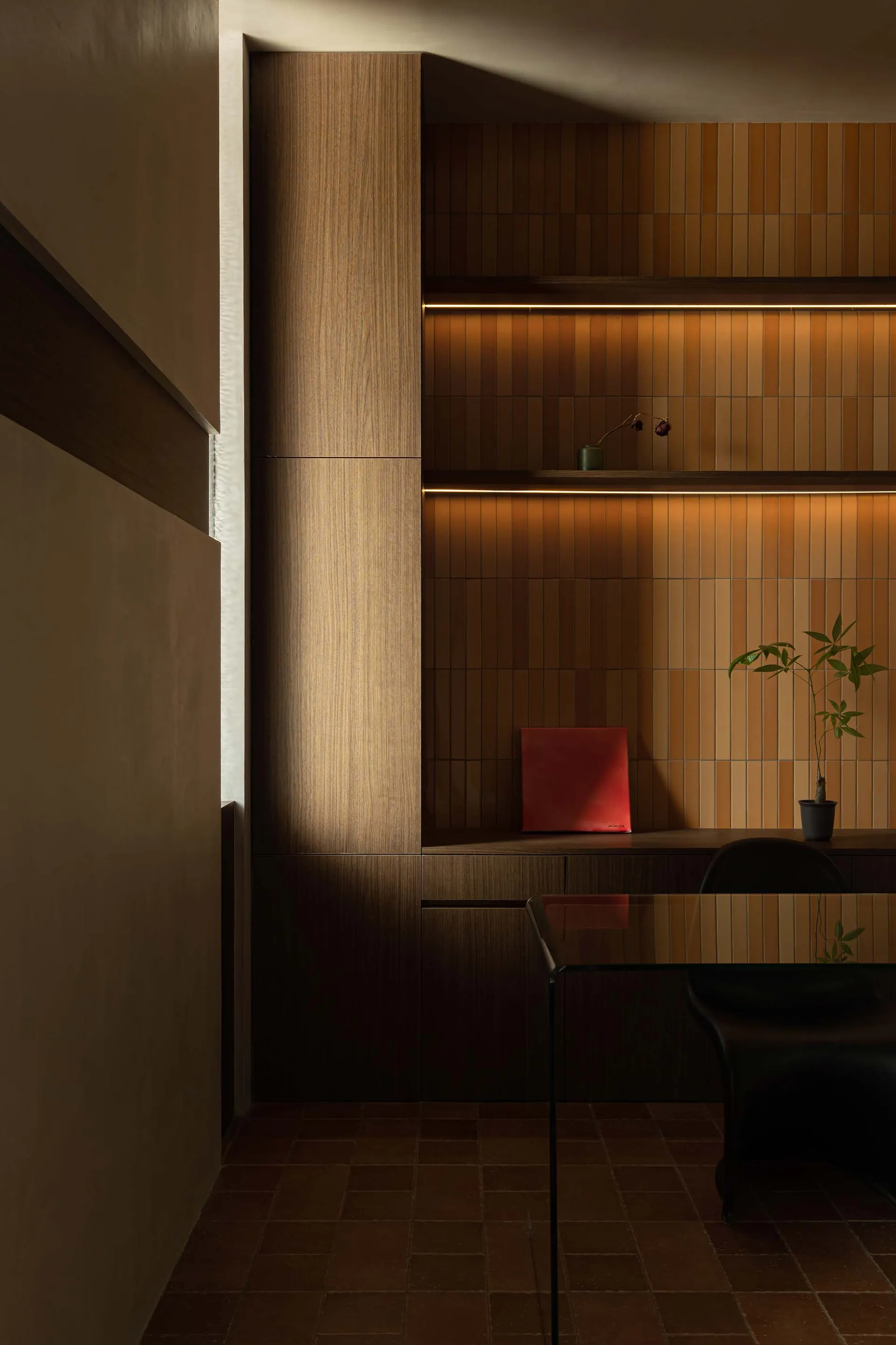 A modern office space featuring wooden paneling with built-in shelves.