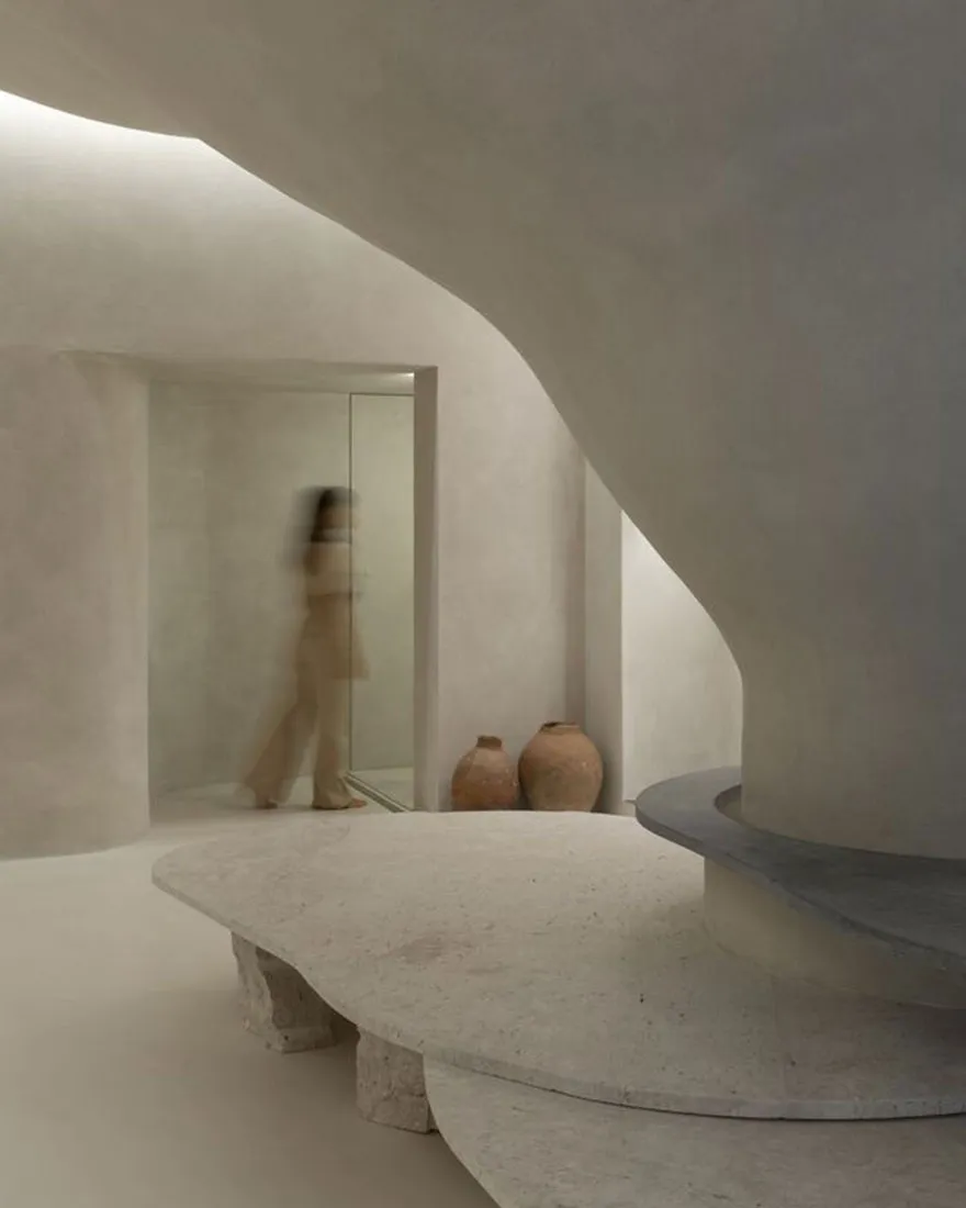 A minimalist, abstract concrete space with smooth, curved surfaces and earthy tones.