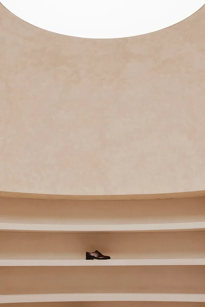 A minimalist shelf made of concrete with a single black shoe on it.