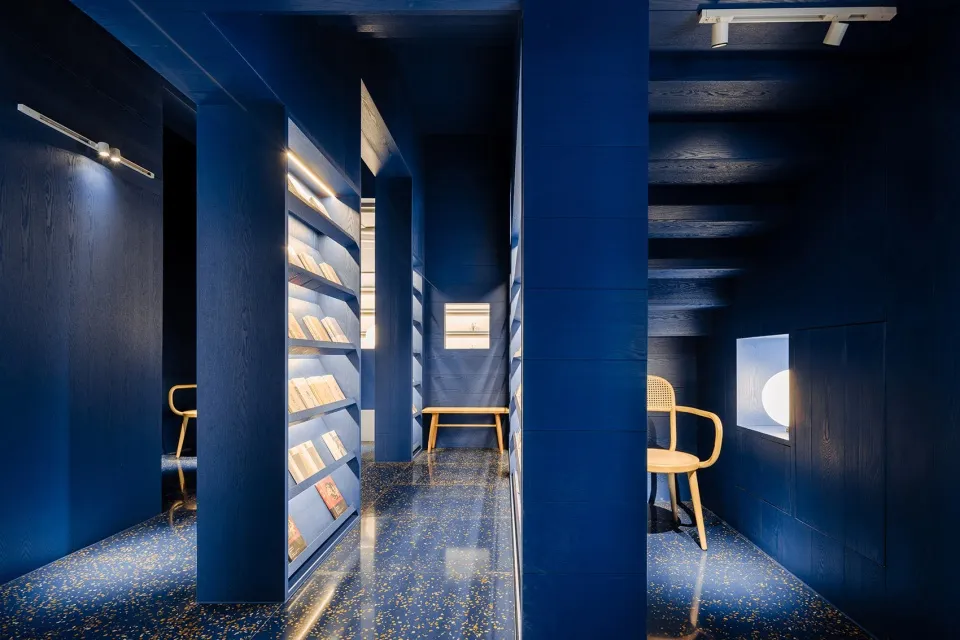 A modern library with blue walls and a porcelain floor.