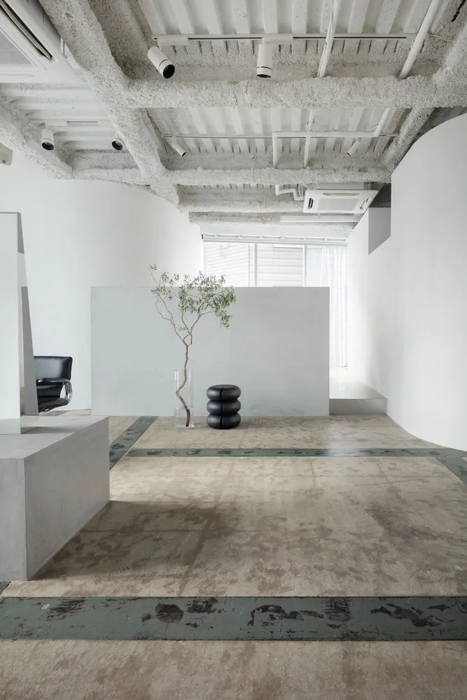A minimalist modern office space with concrete flooring and minimalist furniture.