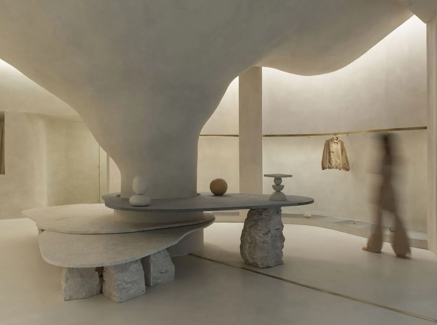 Minimalist retail space featuring a modern concrete countertop and abstract sculptures.
