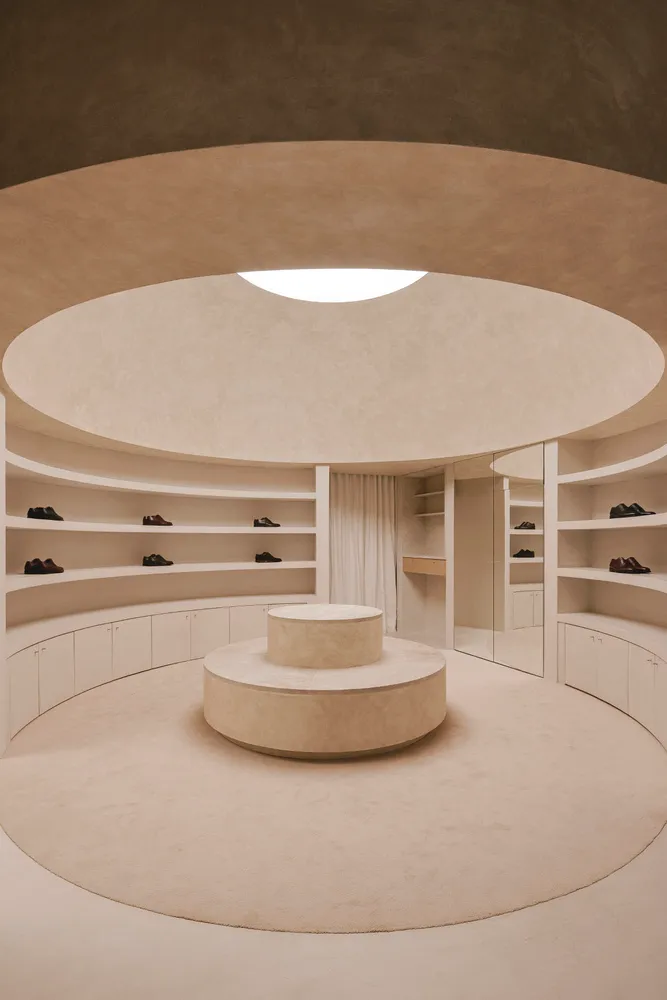 Circular retail storefront interior with concrete floor, glass walls, and minimalist design.