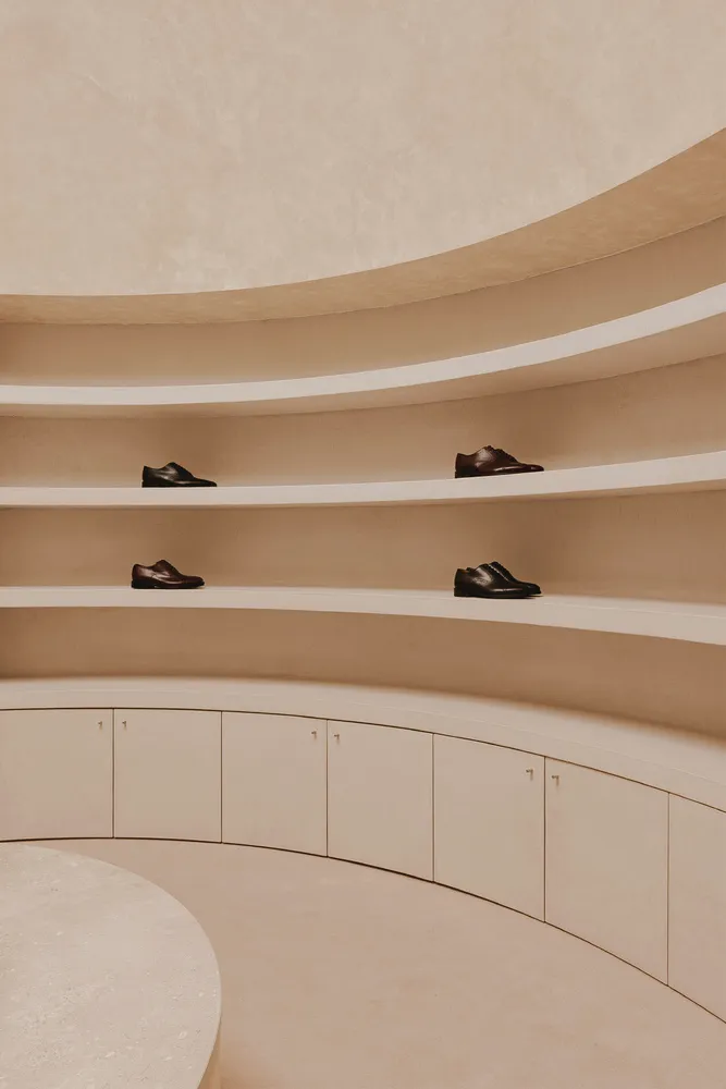 A modern room with a shoe collection displayed on shelves and cabinets made of concrete.