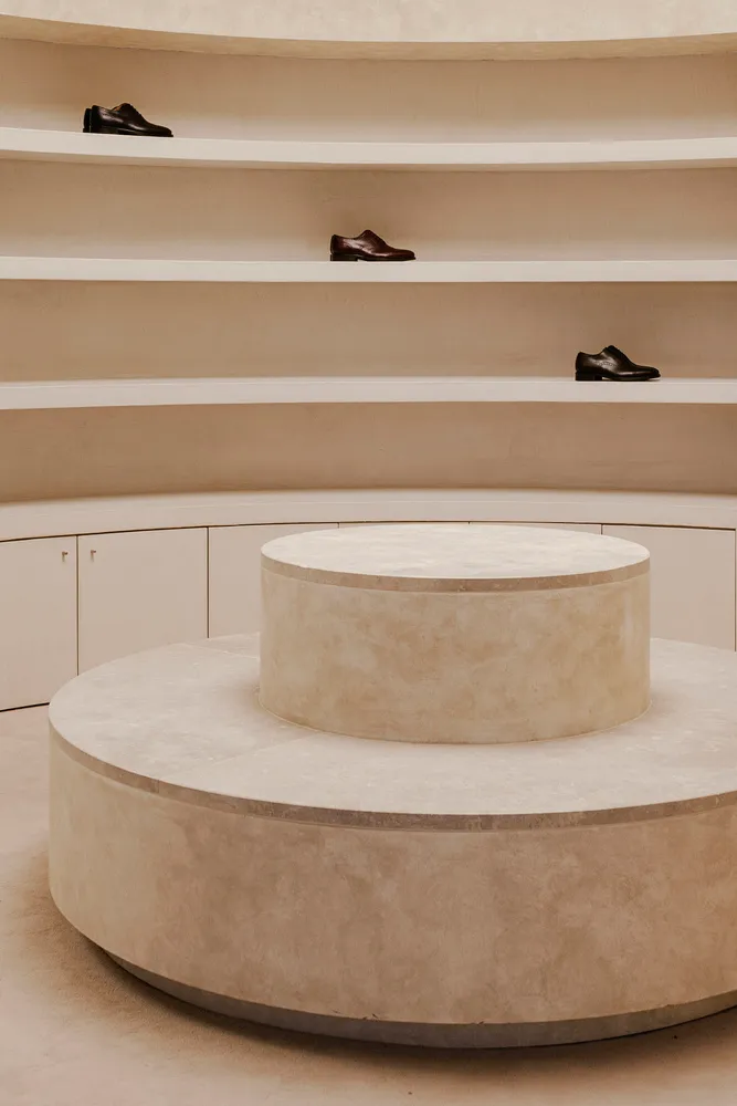 A minimalist shoe display composed of stone and concrete in a modern interior design setting.