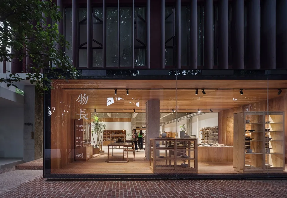 A minimalist retail storefront featuring wooden furniture and glass walls.