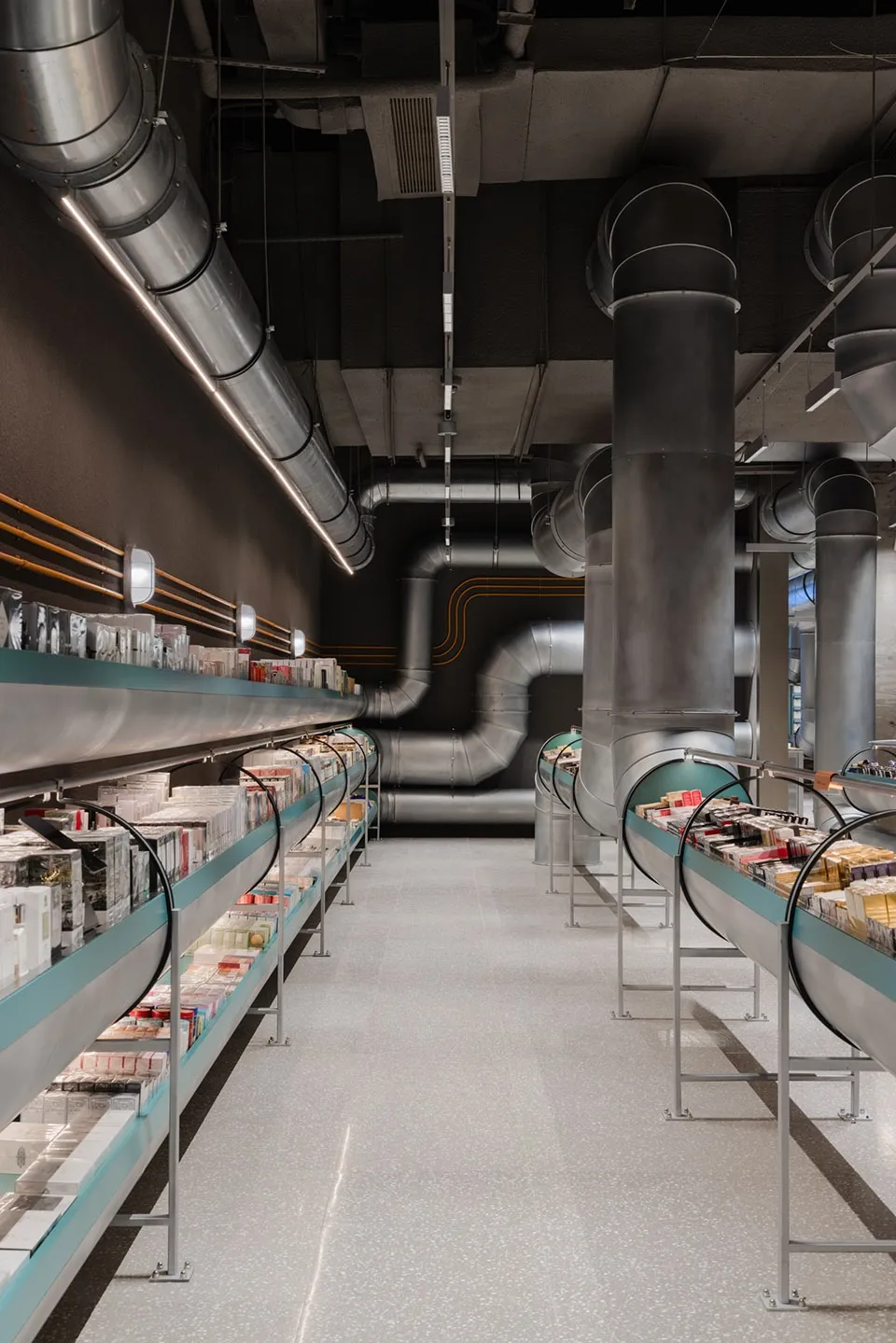 Industrial-style retail store with concrete flooring, metal shelving, and glass pipes.