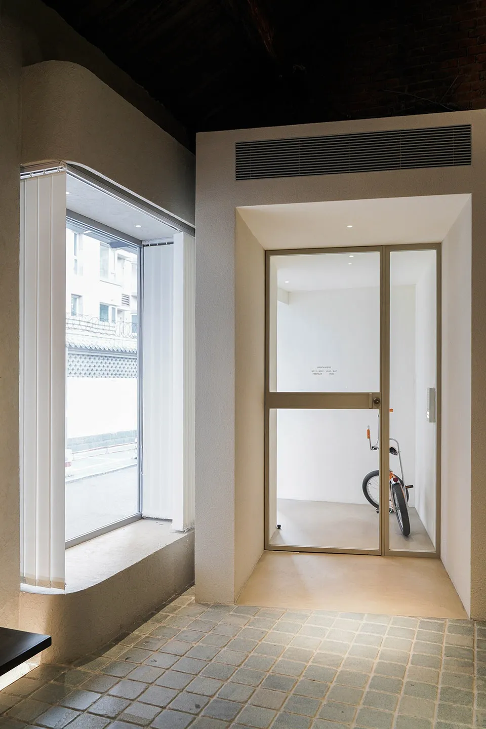 A minimalist entrance featuring a glass door with a bicycle parked inside the room.