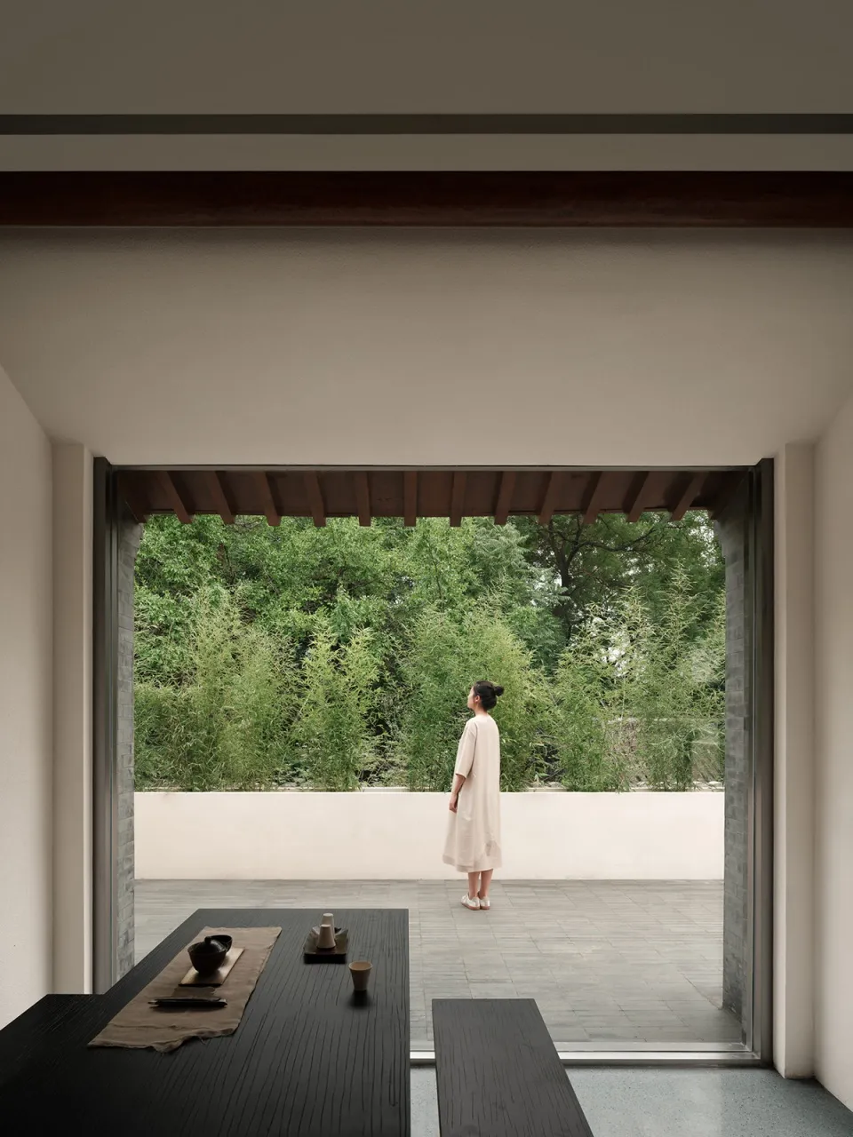 A minimalist interior design featuring a modern wood table with greenery outside the window.