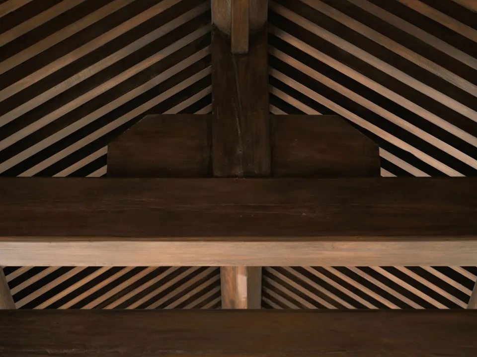 A close-up of a wooden roof structure showing intersecting beams and beams.