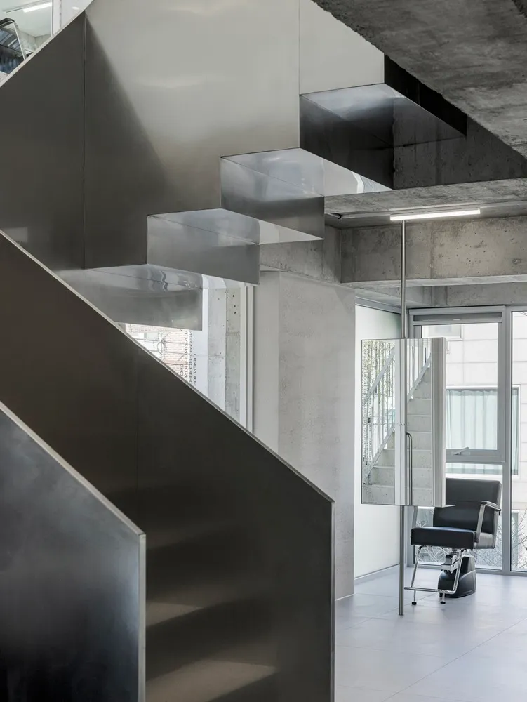 Modern minimalist metallic staircase in an industrial office setting.
