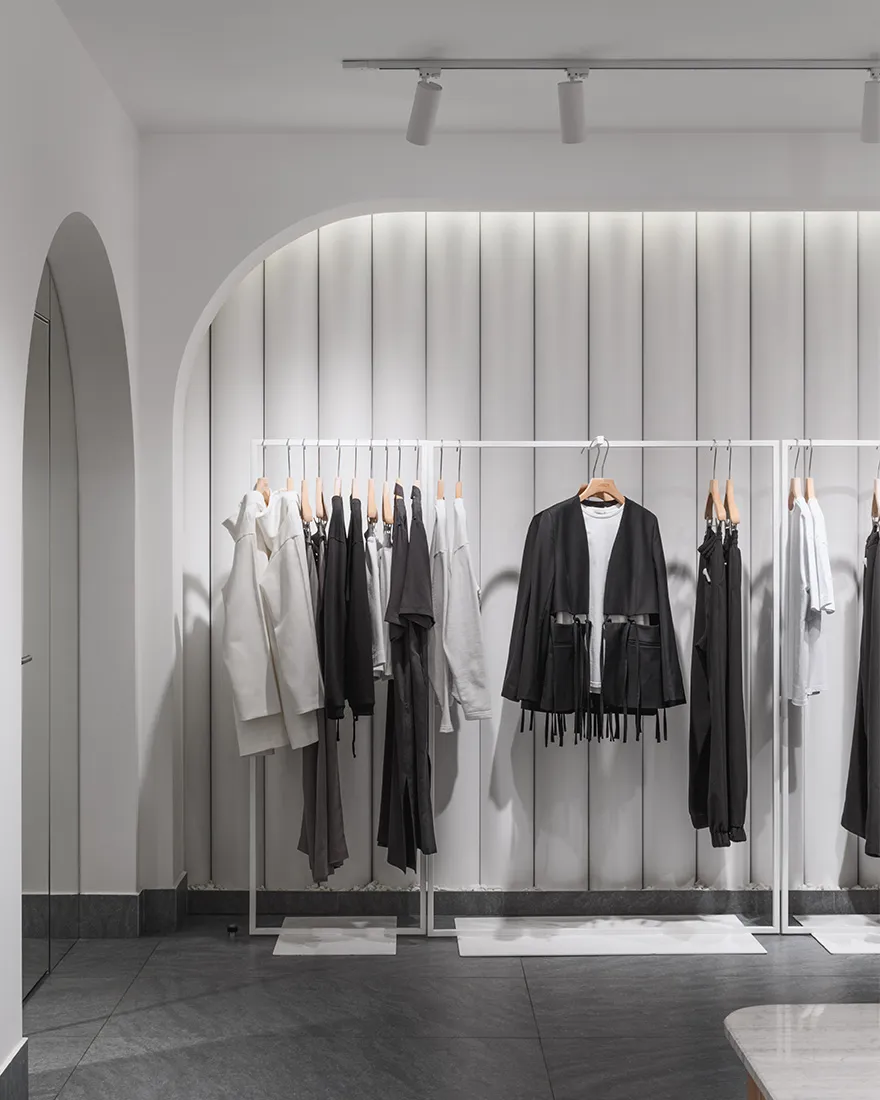 Modern minimalist clothing retail store with metal frames and clothing racks.