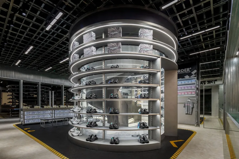 A modern retail shoe store interior with a metal spiral shelving unit displaying shoes.