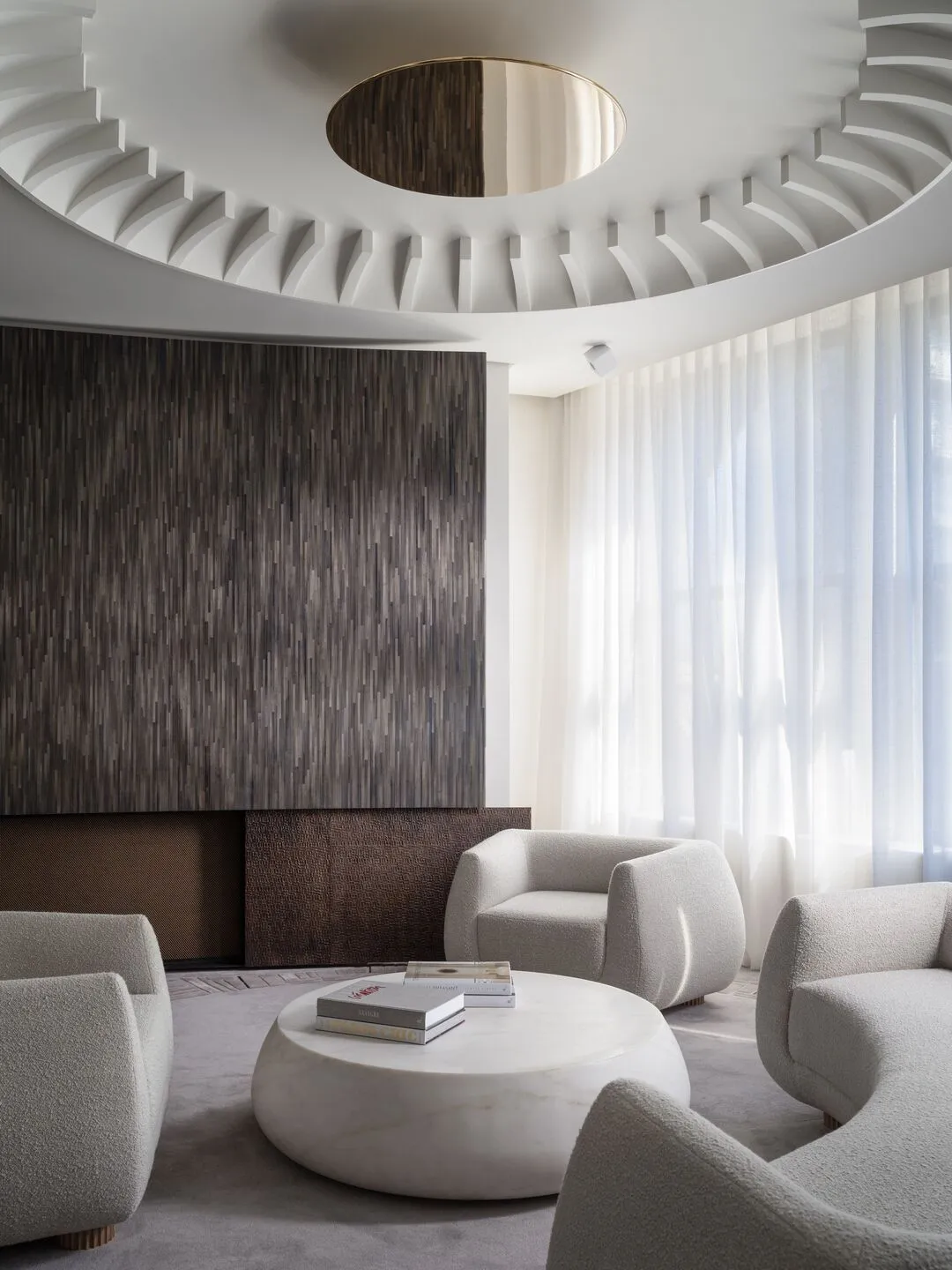 Modern living room with a marble coffee table and textured fabric furniture, featuring circular ceiling design.