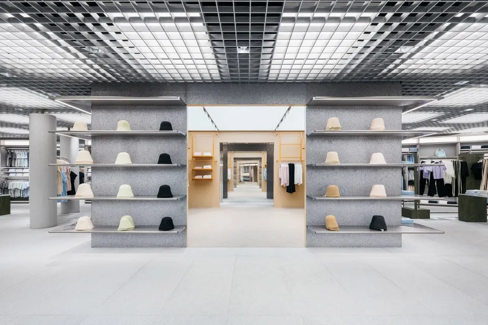A minimalist clothing store with concrete shelves displaying various hats.
